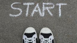 Close-up of sneakers and a 'START' chalk drawing on pavement, symbolizing new beginnings