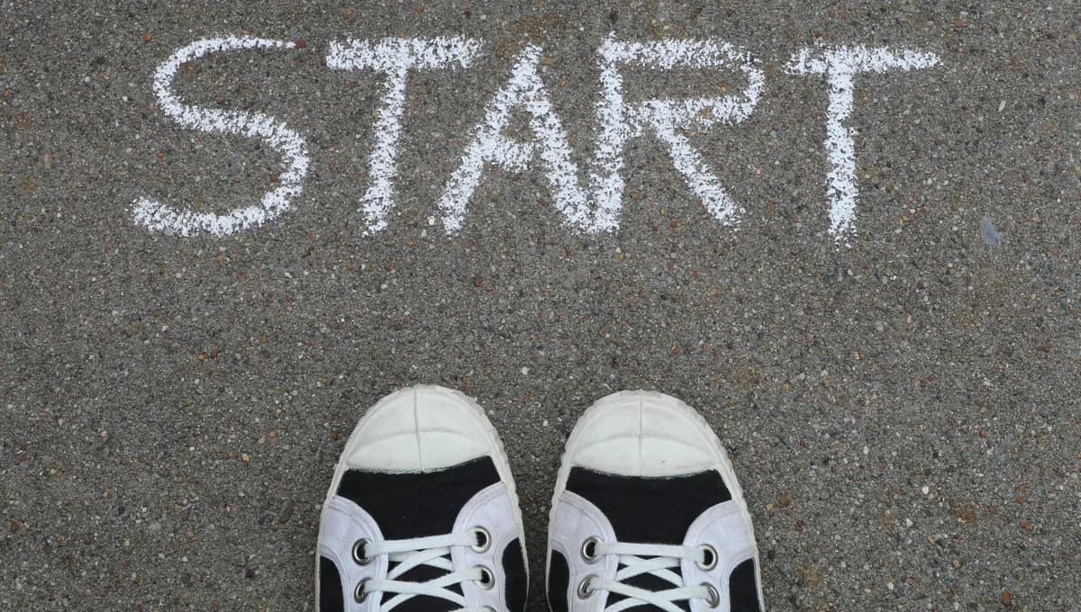 Close-up of sneakers and a 'START' chalk drawing on pavement, symbolizing new beginnings